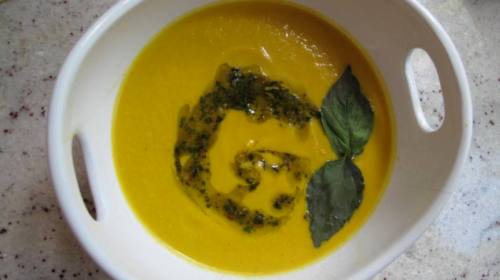 Carrot Ginger Cashew Bisque with vegan pesto and basil leaves.